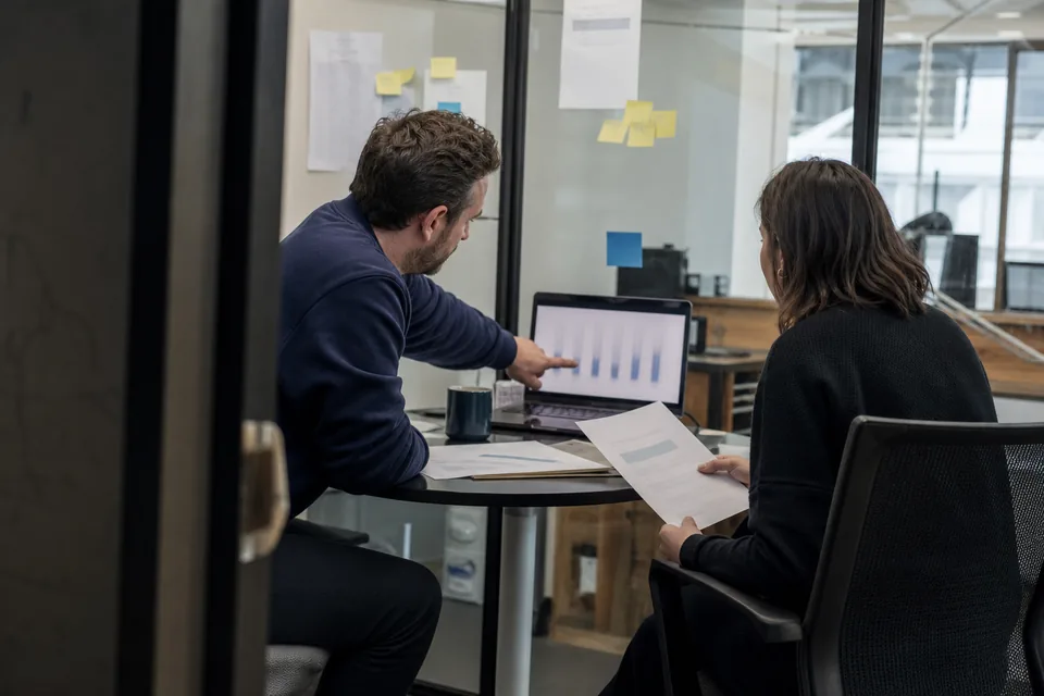 Finance lead and founder comparing a printed invoice with costs on a laptop