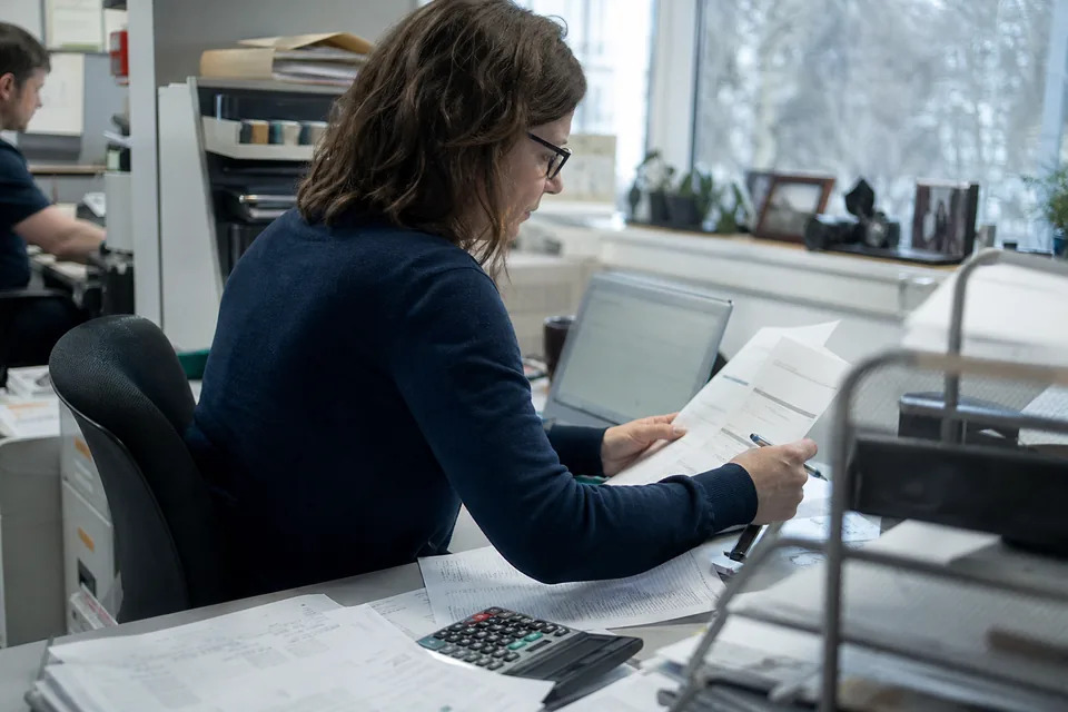 Operations manager comparing printed invoices with figures on a laptop and a calculator