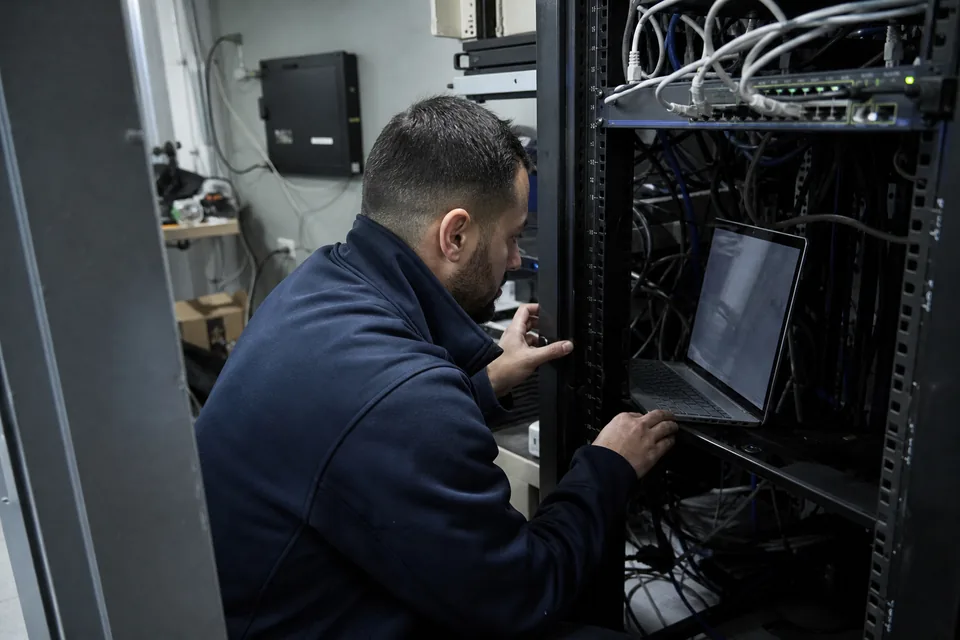 IT administrator checking access settings on a laptop in a server closet